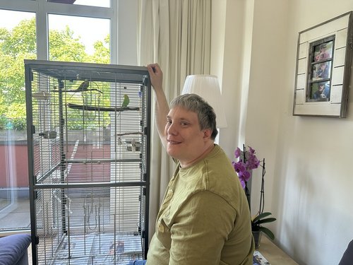 Bewohner sitzt neben einem Vogelkäfig