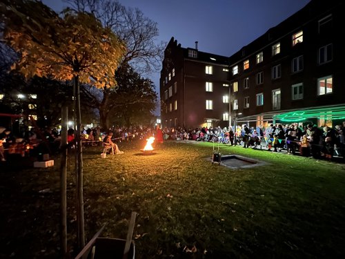 Viele Menschen stehe um das Martinsfeuer, wo gleichzeitig die Martinsgeschichte vorgeführt wird