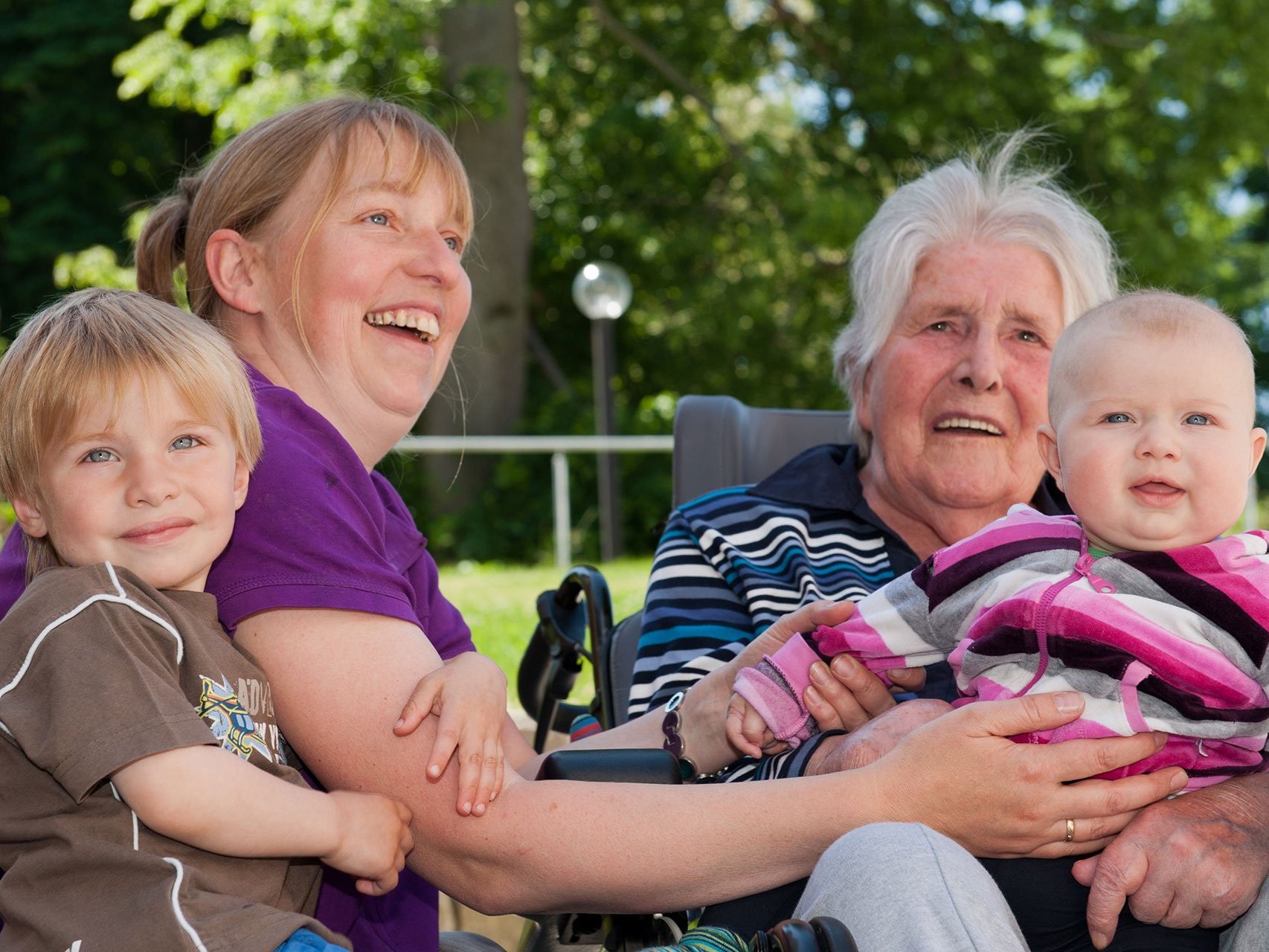 Eine Bewohnerin im Rollstuhl hat Besuch von ihrer Tochter und den zwei Enkelkindern.