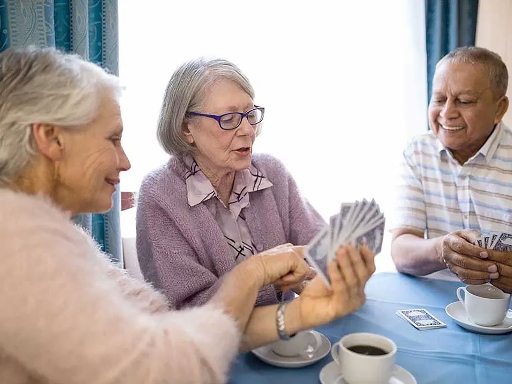 Drei Bewohner sitzen gemeinsam an einem Tisch und spielen Karten.