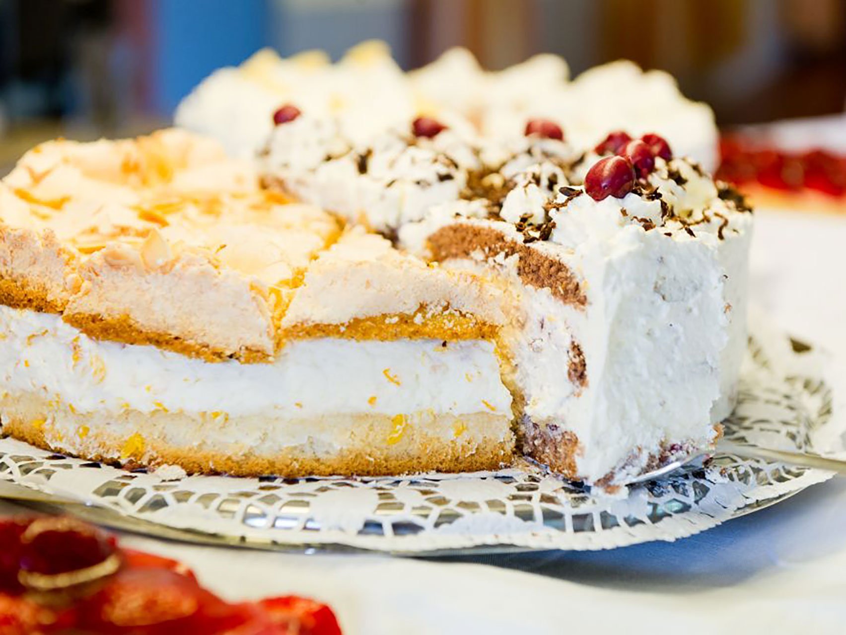 Eine Nahaufnahme einer aufgeschnittenen Torte mit Sahne und Kirschen