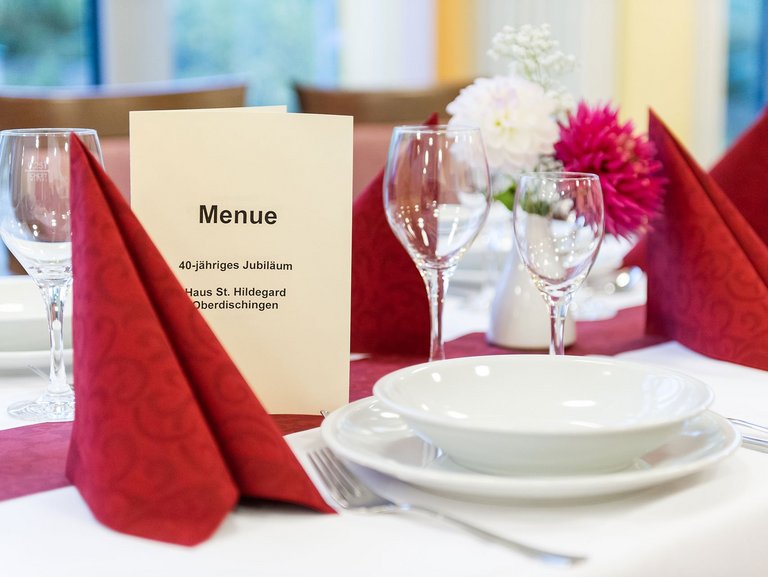 Ein festlich gedeckter Tisch mit einer Menükarte und roten Servietten