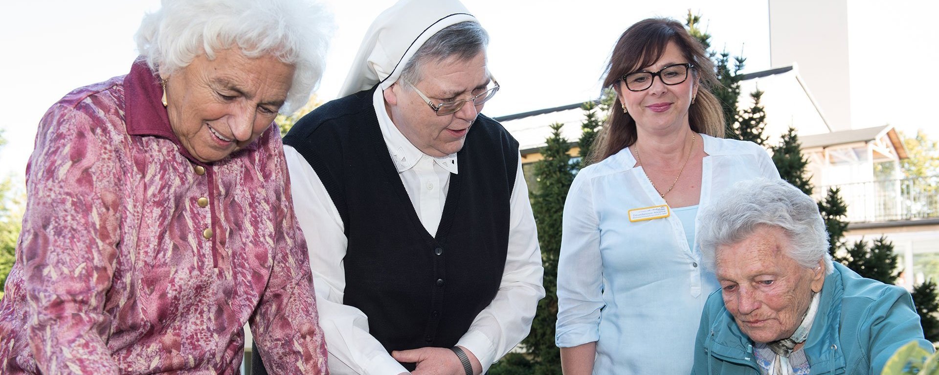 Eine Ordensschwester und eine Mitarbeiterin vom Altenheim Oberdischingen helfen zwei Bewohnern beim Pflanzen