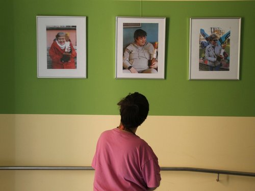 Ein Mitarbeiterin schaut sich drei Fotos an der Wand an, alle drei Fotos zeigen eine Bewohnerin mit einen Königs Skulptur 